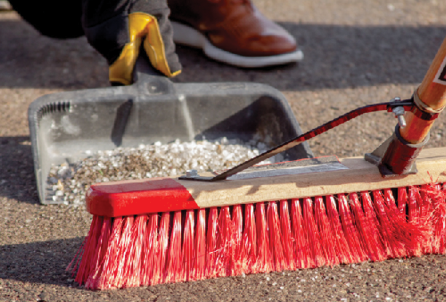 A person cleans up excess salt from their sidewalk in the winter